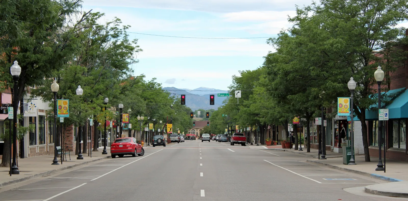 Tree-lined historic Main Street in downtown Littleton, with the foothills in the distance